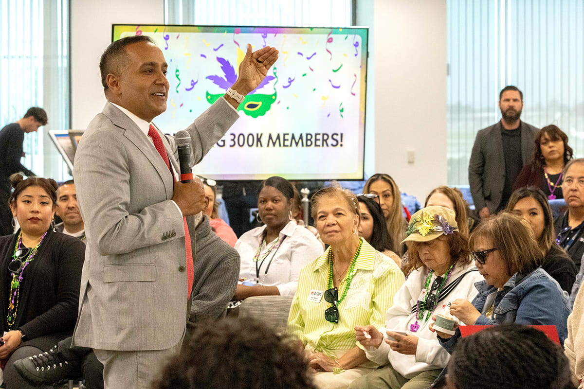 Man in suit addresses a small room of people.